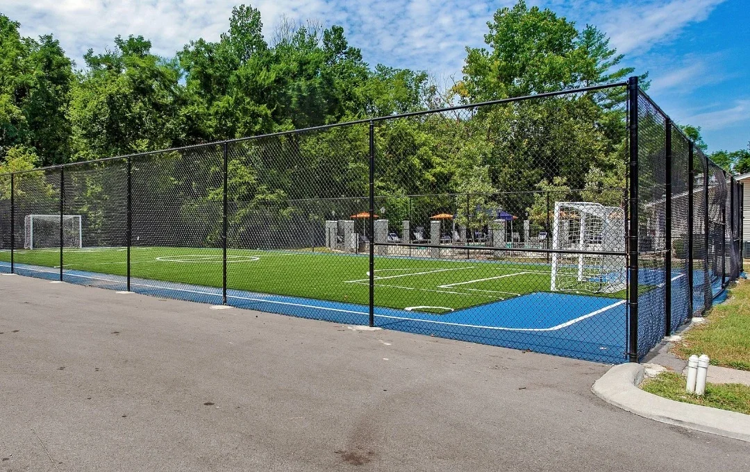 a soccer field with a fence and trees at The Stone Ridge