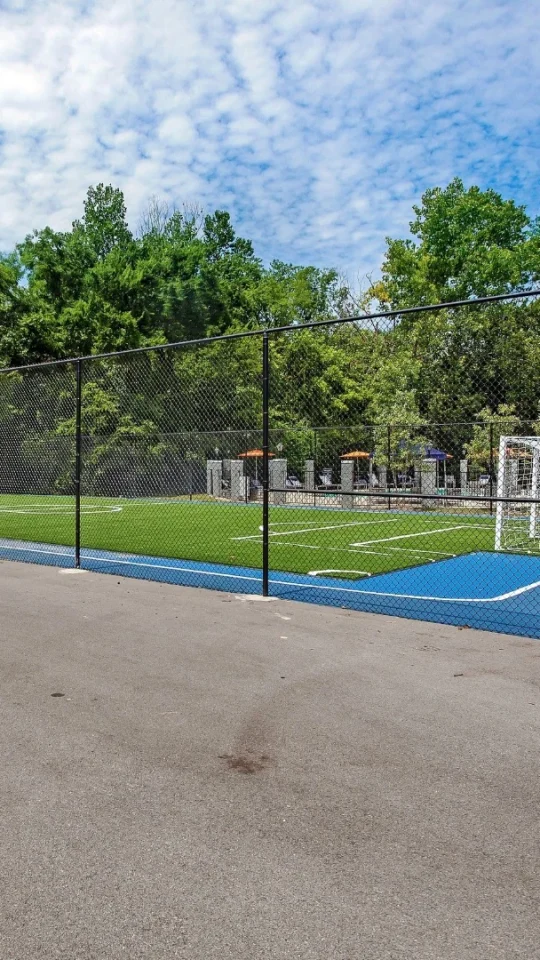 a soccer field with a fence and trees at The Stone Ridge